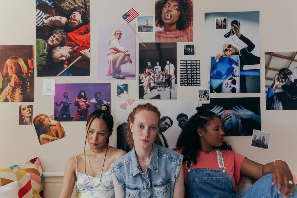 Three teenage girls relaxing in a stylish, poster-filled bedroom. Ideal for lifestyle and fashion themes.